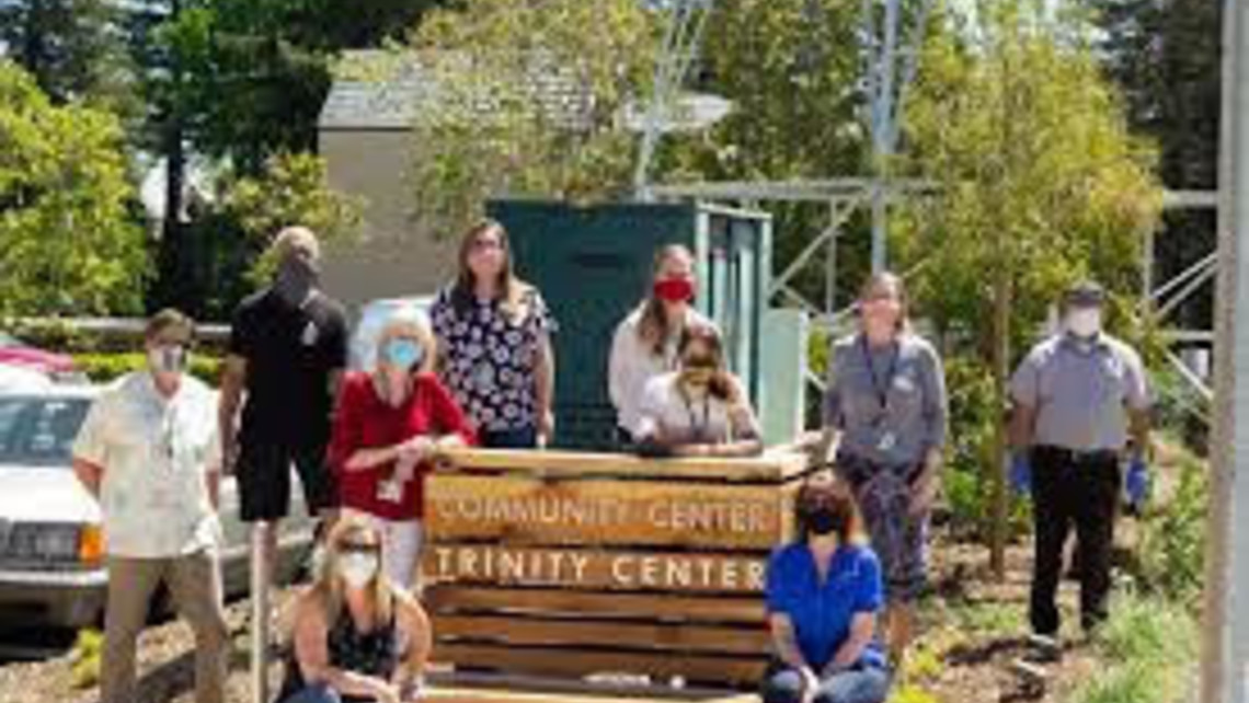 Photo of volunteers standing near sign for Trinity Center